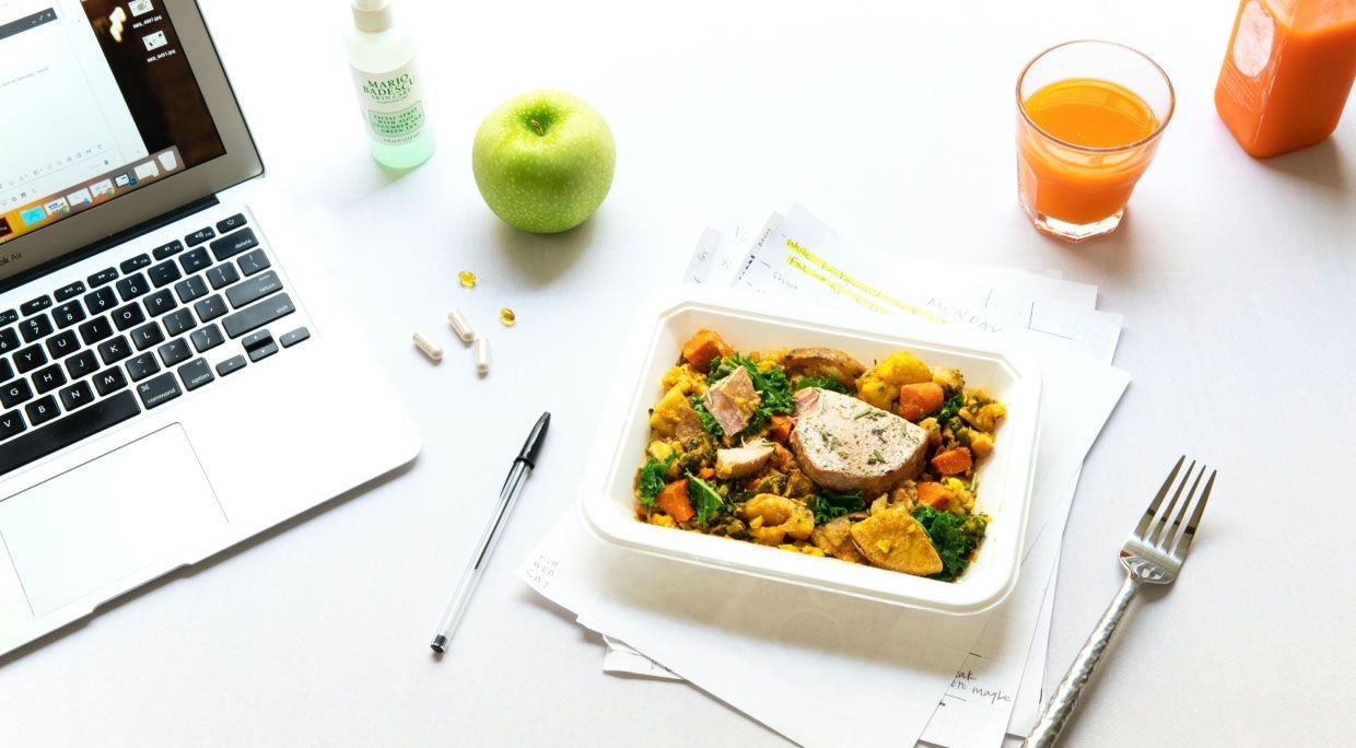 tray of food on desk next to laptop