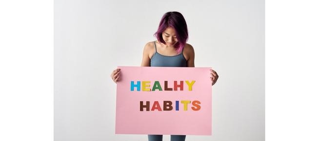 person holding colorful healthy habits sign